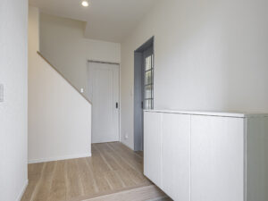 玄関ホールは、飽きのこない暖色系シンプルな色合いで仕上げました。リビングの入口は、ワンポイントのアクセント色のドアを採用されました。